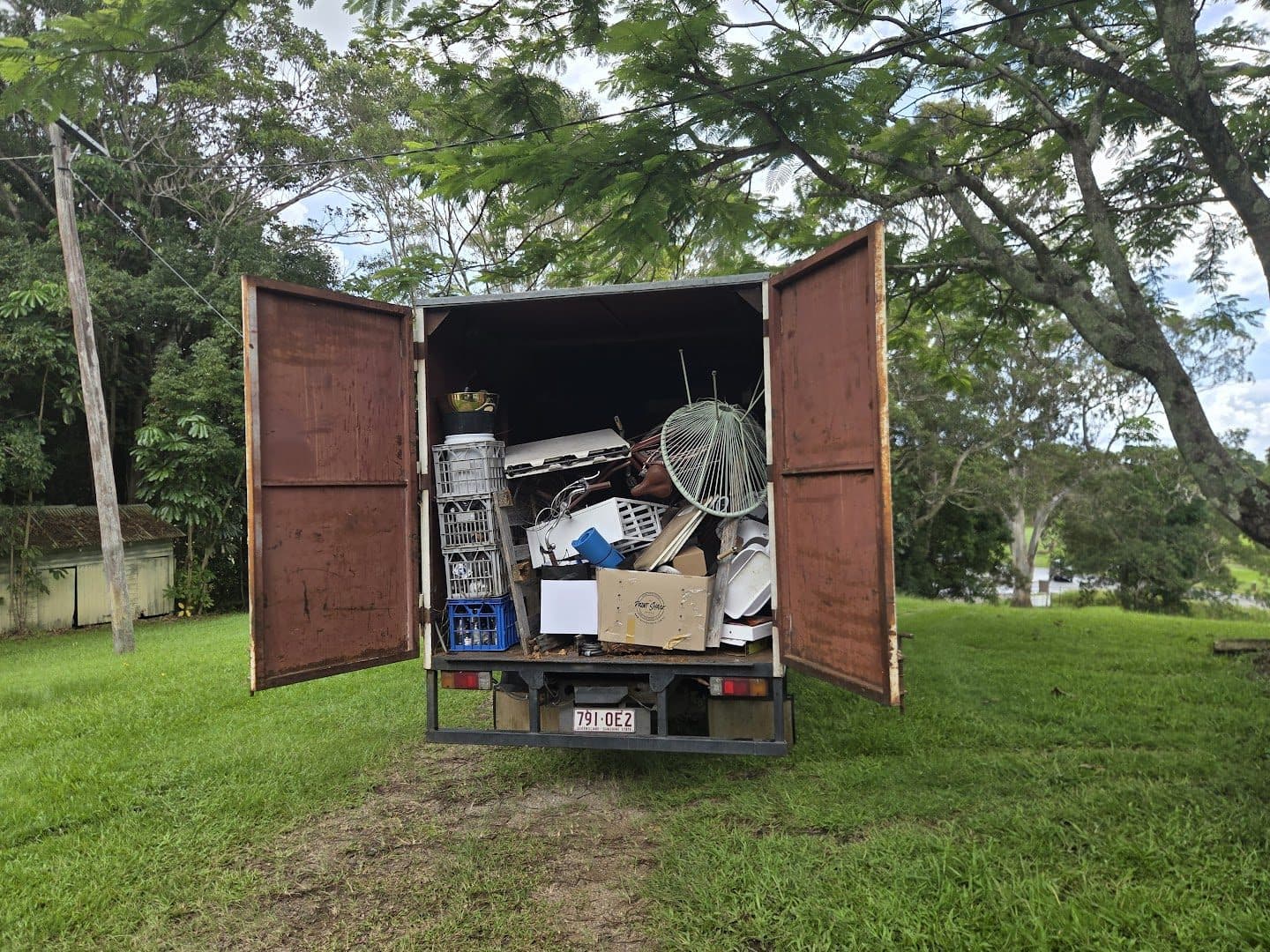 The truck rear doors open, loaded with a full household clear-out