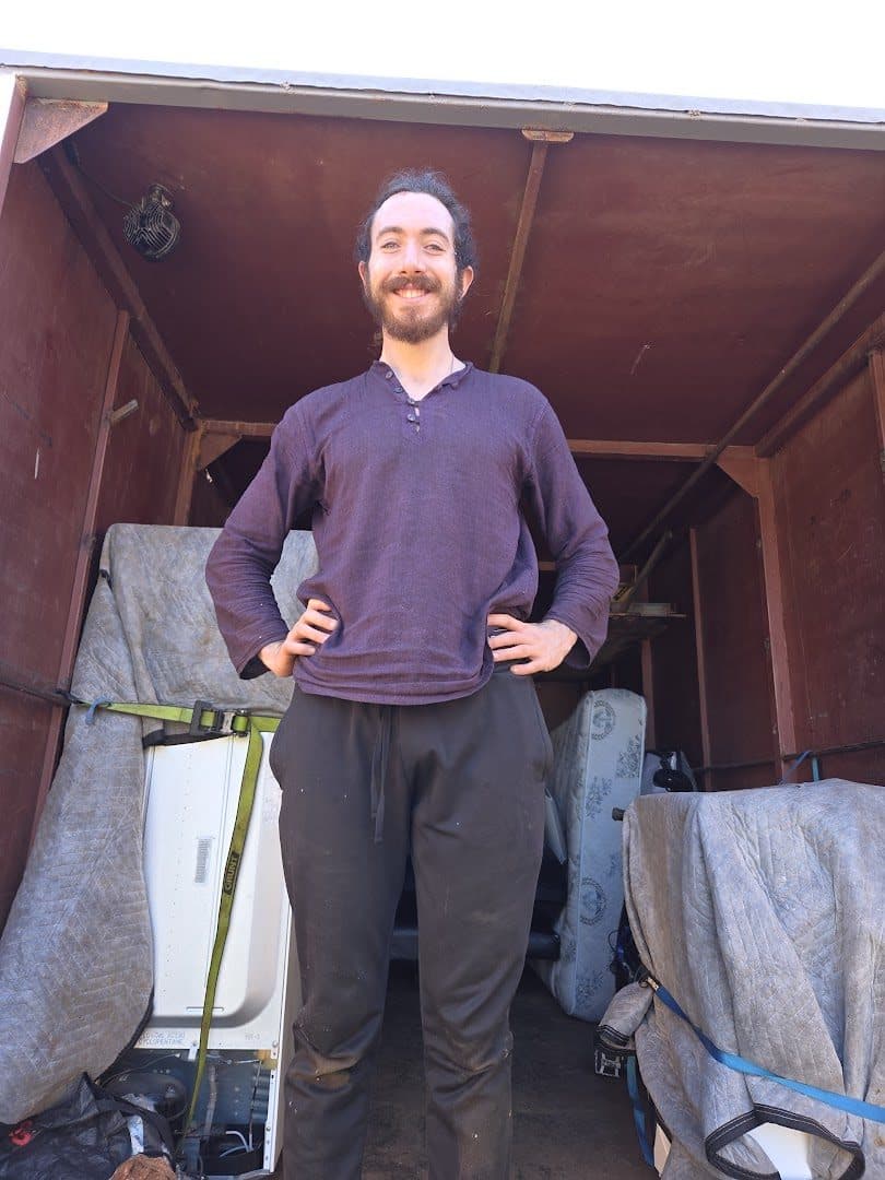 Crew member standing in the truck doorway with wrapped loads and a mattress behind