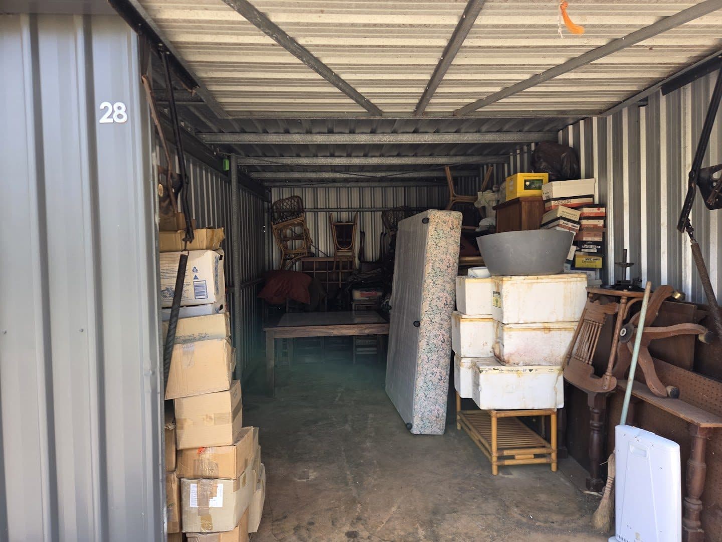 A storage unit stacked with boxes, a mattress base and furniture