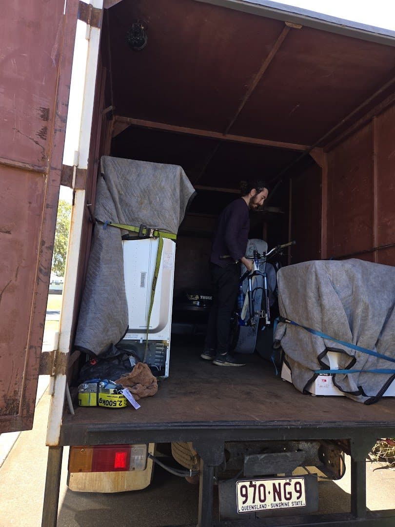 Crew member positioning a bike between wrapped appliances in the truck